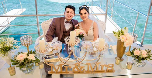 Newlyweds celebrating at their decorated wedding table aboard a boat