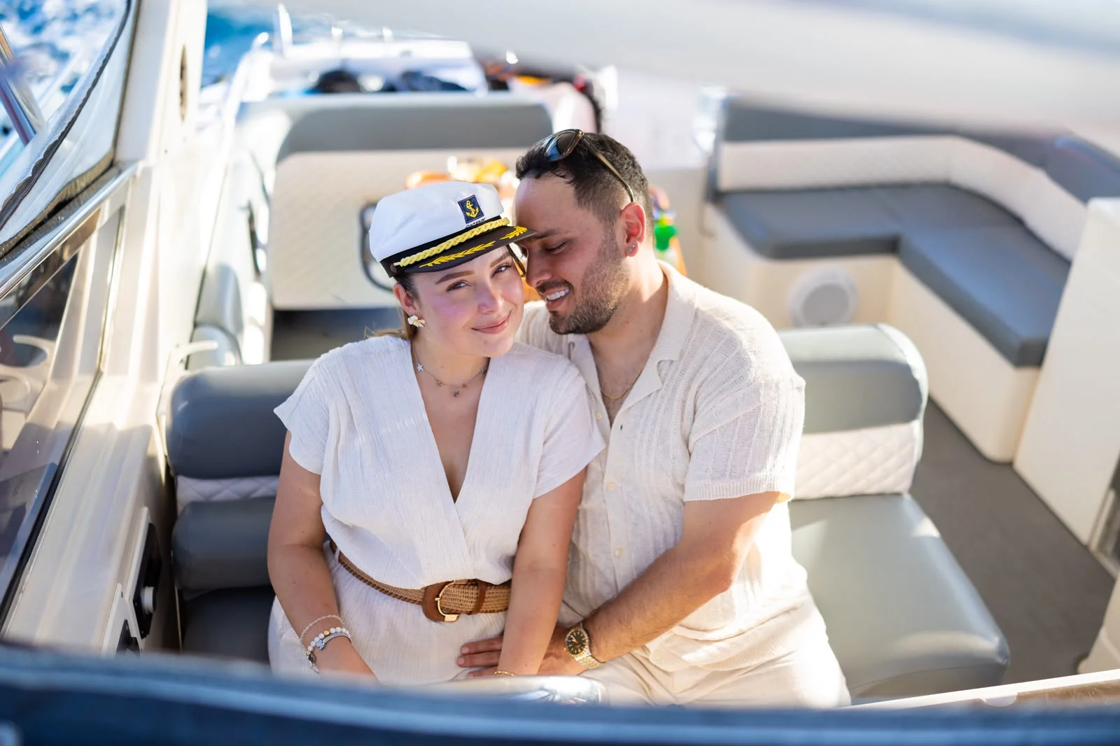 Couple seated on board wearing a captain’s hat
